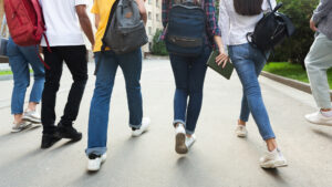 Unrecognizable teenage students on a campus walking